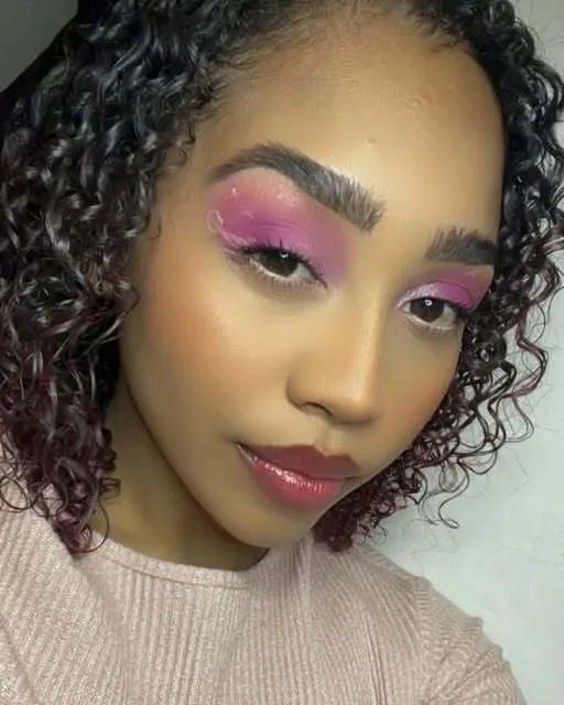 Close portrait with bright pink eyeshadow, defined brows, and a glossy lip.